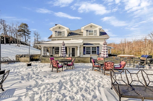 snow covered back of property featuring a hot tub