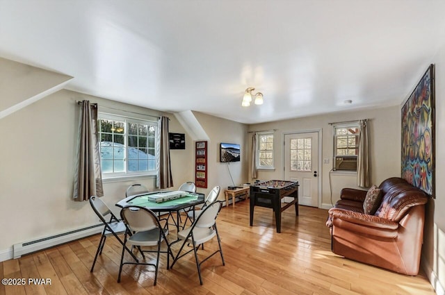 dining space featuring a baseboard heating unit, cooling unit, and light hardwood / wood-style floors