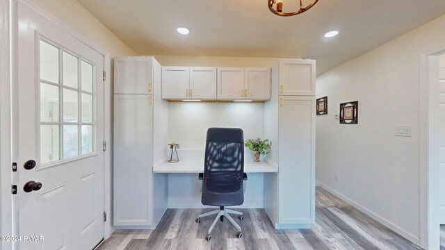 office space with light wood-type flooring, a wealth of natural light, and built in desk