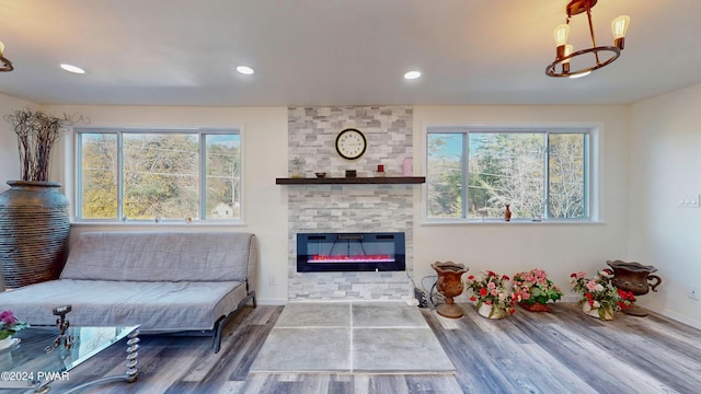 living room with a stone fireplace, plenty of natural light, and hardwood / wood-style flooring