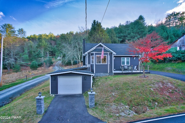 view of front facade featuring a deck, a garage, a front lawn, and an outdoor structure