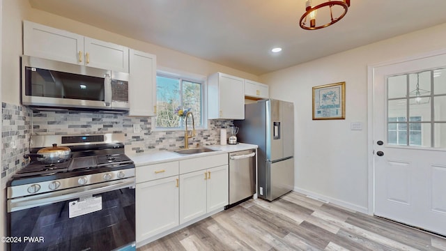 kitchen with decorative backsplash, stainless steel appliances, sink, light hardwood / wood-style flooring, and white cabinetry