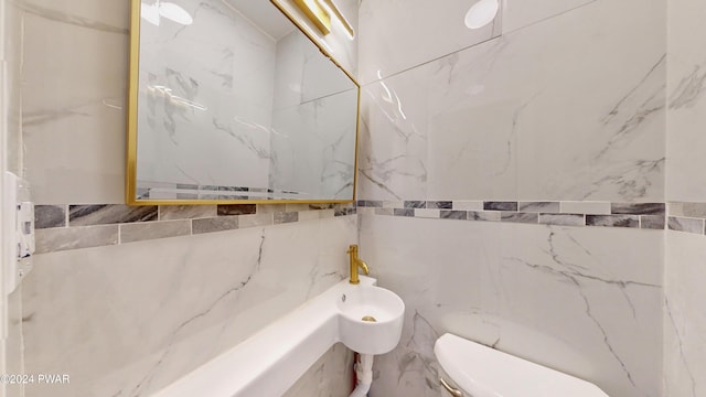 bathroom featuring tile walls and toilet