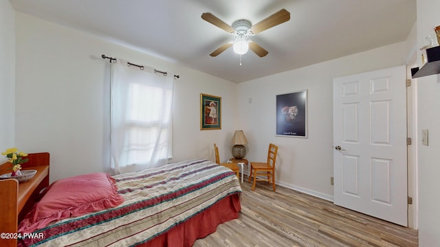 bedroom with ceiling fan, light hardwood / wood-style flooring, and multiple windows