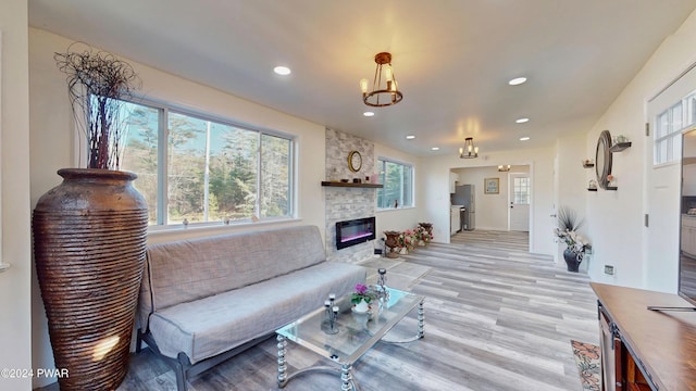 living room with a fireplace, a notable chandelier, and light wood-type flooring