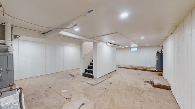 basement with electric water heater and wood walls