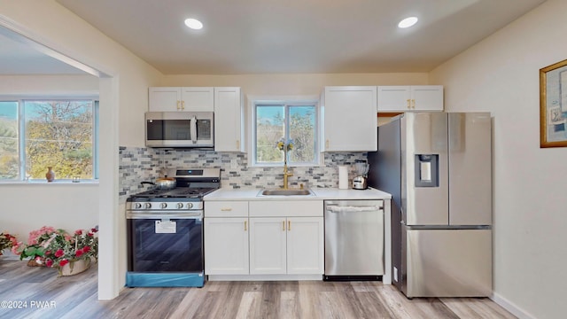 kitchen with white cabinets, sink, stainless steel appliances, and tasteful backsplash