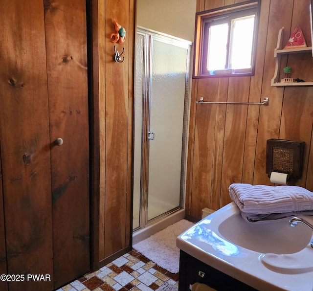 bathroom with wooden walls, a stall shower, and vanity