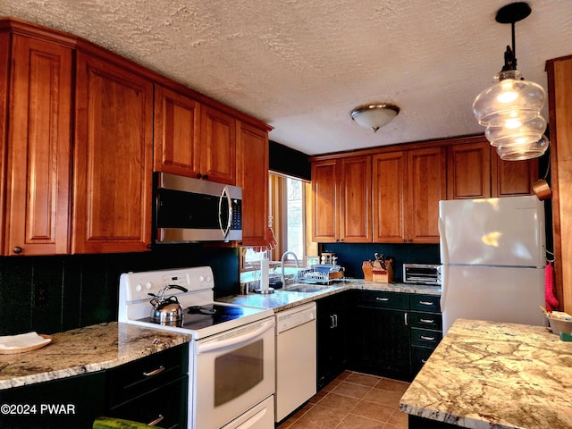 kitchen featuring light tile patterned floors, hanging light fixtures, brown cabinetry, white appliances, and a textured ceiling