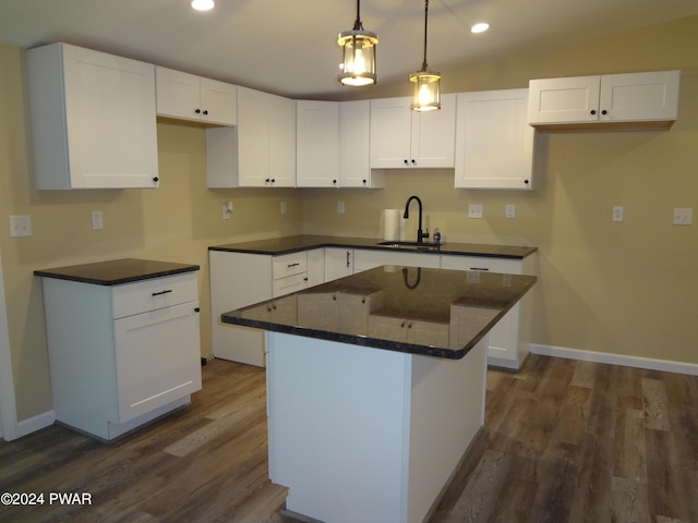 kitchen featuring dark wood-style floors, a center island, white cabinets, and a sink