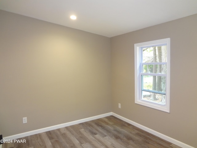 spare room with baseboards, wood finished floors, and recessed lighting