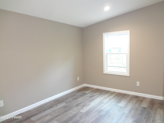 spare room featuring lofted ceiling, wood finished floors, and baseboards