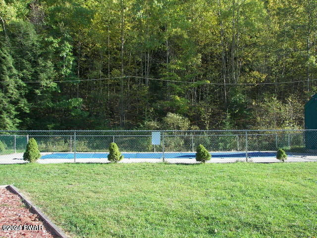 view of home's community with a yard, a swimming pool, and fence