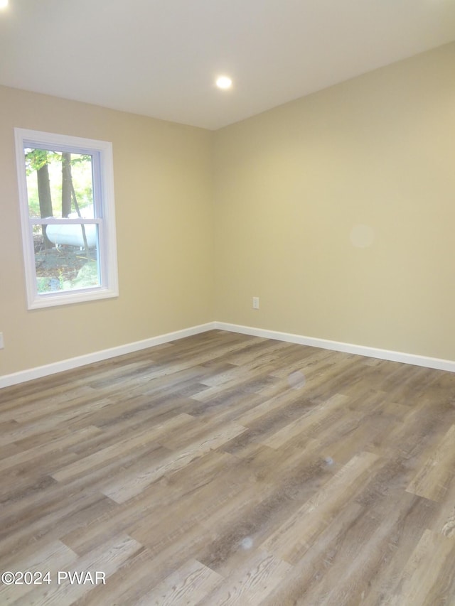 unfurnished room with recessed lighting, wood finished floors, and baseboards