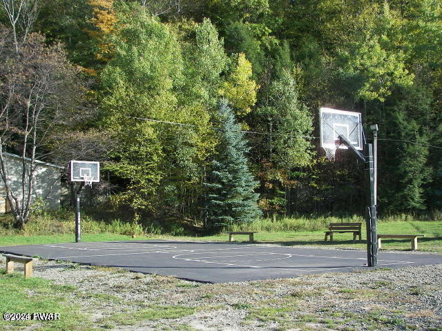 view of sport court with community basketball court and a wooded view