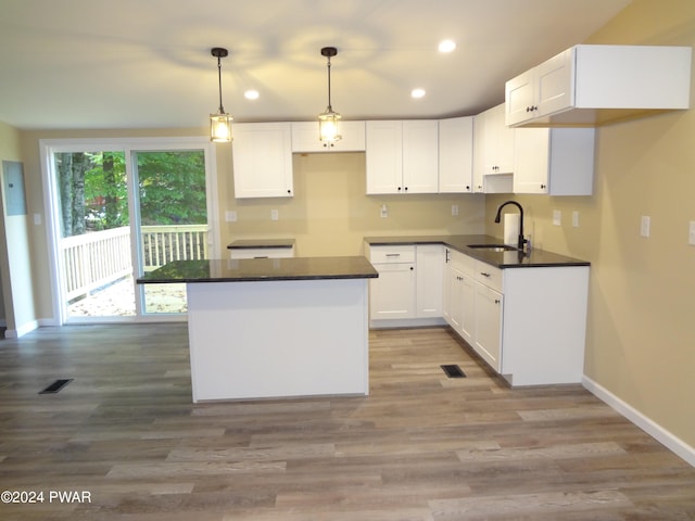 kitchen with a center island, dark countertops, recessed lighting, white cabinetry, and a sink