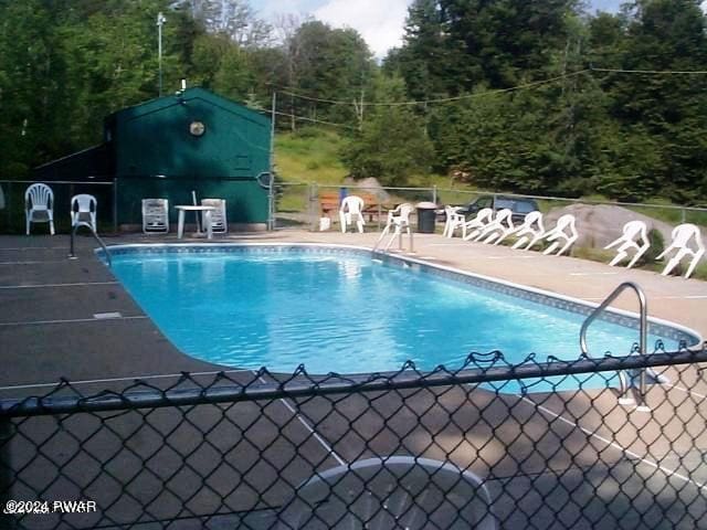 community pool with fence and a patio