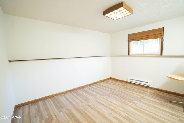 spare room featuring light wood-type flooring and a baseboard heating unit