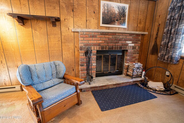 sitting room featuring wooden walls, carpet floors, a baseboard radiator, and a brick fireplace