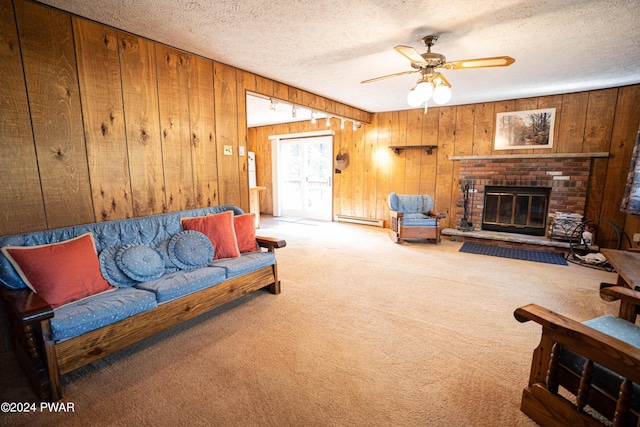 living room with wood walls, a textured ceiling, a fireplace, a baseboard radiator, and light colored carpet