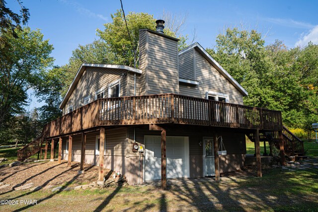 rear view of property featuring a garage and a wooden deck