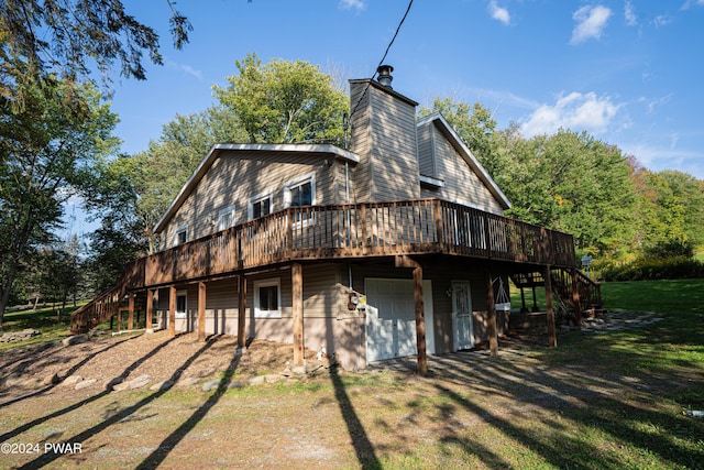 back of house featuring a lawn, a garage, and a wooden deck