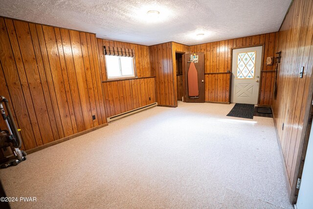 carpeted entryway featuring wooden walls, a textured ceiling, and a baseboard heating unit