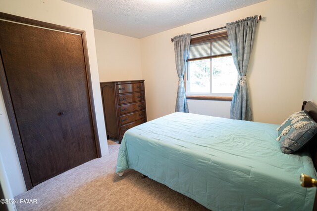 carpeted bedroom featuring a textured ceiling and a closet