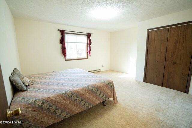 carpeted bedroom featuring baseboard heating, a closet, and a textured ceiling