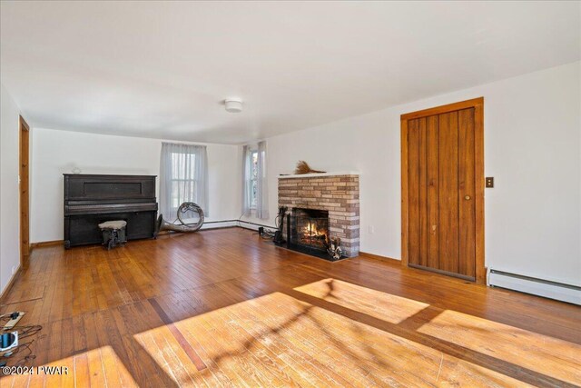 unfurnished living room featuring a fireplace, wood-type flooring, and a baseboard radiator