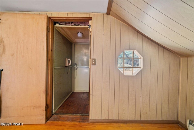 hall featuring baseboard heating, wooden walls, and light wood-type flooring