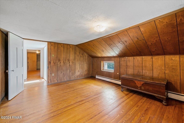 additional living space featuring a baseboard radiator, wooden ceiling, light hardwood / wood-style floors, lofted ceiling, and wood walls