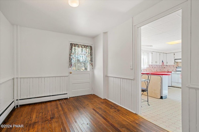 empty room with a baseboard radiator and dark hardwood / wood-style floors