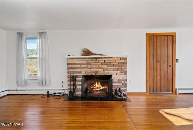 living room featuring a stone fireplace, hardwood / wood-style floors, and a baseboard radiator