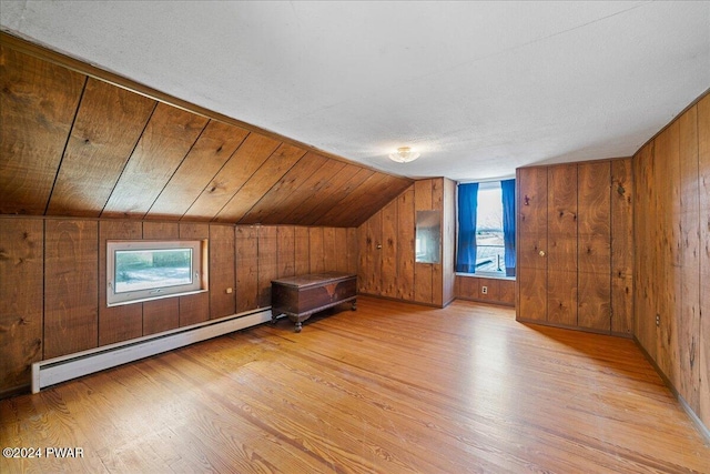 additional living space featuring a baseboard radiator, lofted ceiling, wooden walls, wood ceiling, and light wood-type flooring