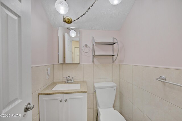 116 Rainbow Dr, Lackawaxen, PA 18435 - bathroom featuring vanity, toilet, a textured ceiling, a wainscoted wall, and tile walls