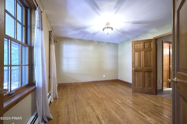 unfurnished room with a baseboard radiator and light wood-type flooring