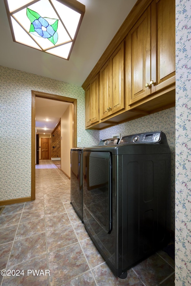 clothes washing area with separate washer and dryer and cabinets