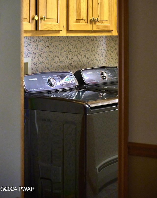 clothes washing area with cabinets and washing machine and clothes dryer