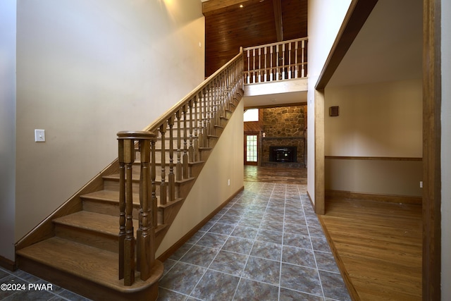 staircase with a stone fireplace and a towering ceiling