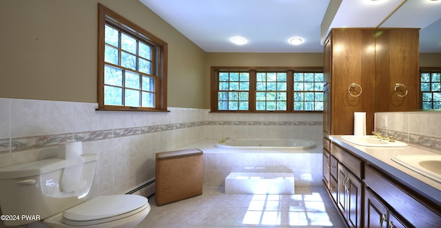 bathroom featuring a baseboard radiator, tile patterned floors, tiled bath, vanity, and tile walls