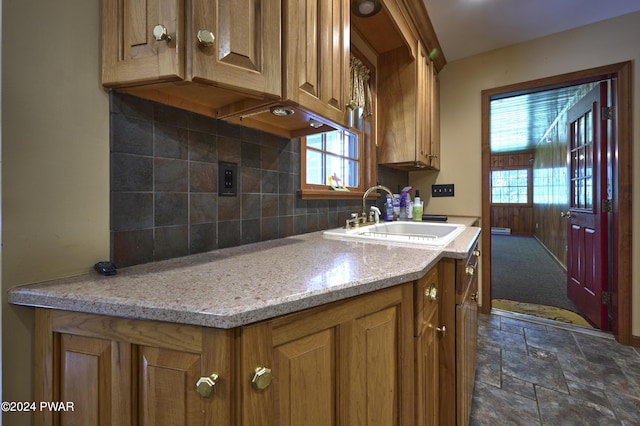 kitchen with backsplash, light stone counters, a wealth of natural light, and sink