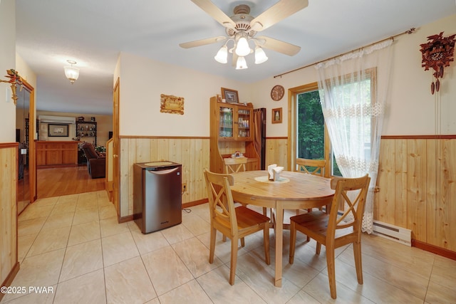 380 Falling Waters Blvd, Lackawaxen, PA 18435 - dining space featuring wainscoting, wood walls, a baseboard radiator, a ceiling fan, and light tile patterned flooring