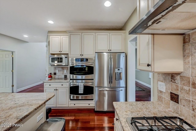 kitchen with decorative backsplash, light stone counters, dark wood-type flooring, extractor fan, and stainless steel appliances