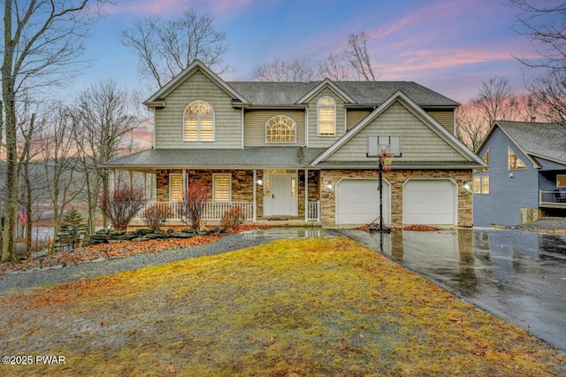 view of front of house featuring an attached garage, covered porch, a shingled roof, driveway, and stone siding