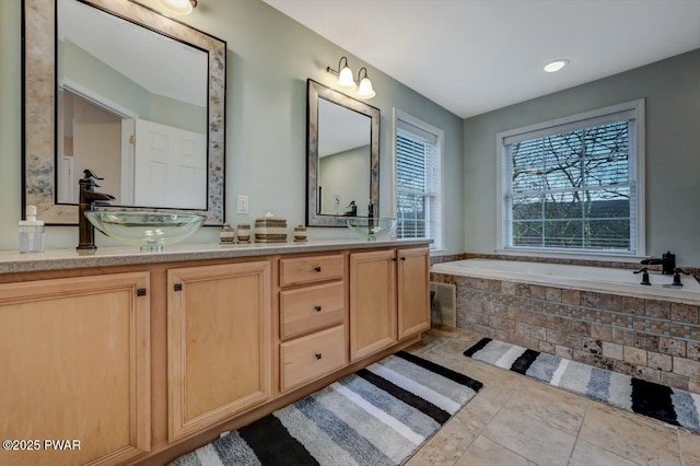 bathroom featuring a sink, a bath, and double vanity