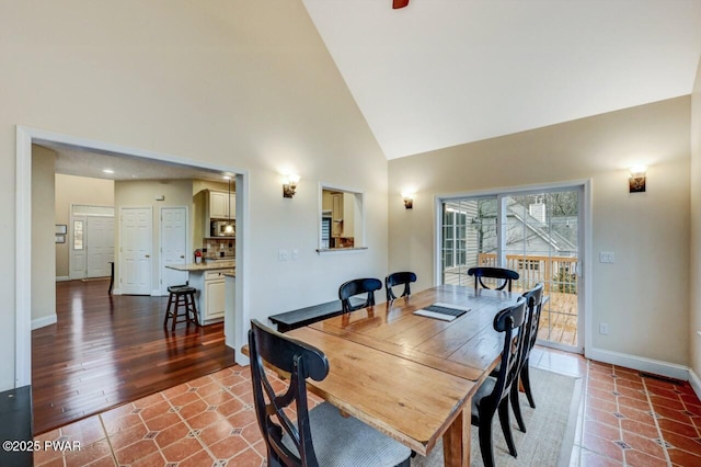 dining area with high vaulted ceiling, tile patterned floors, and baseboards