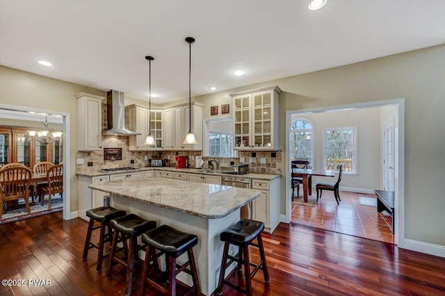 kitchen with wall chimney range hood, tasteful backsplash, appliances with stainless steel finishes, and a center island