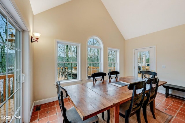 tiled dining space with high vaulted ceiling, baseboards, and visible vents