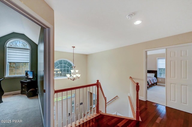 hallway with a wealth of natural light, baseboards, a notable chandelier, and an upstairs landing